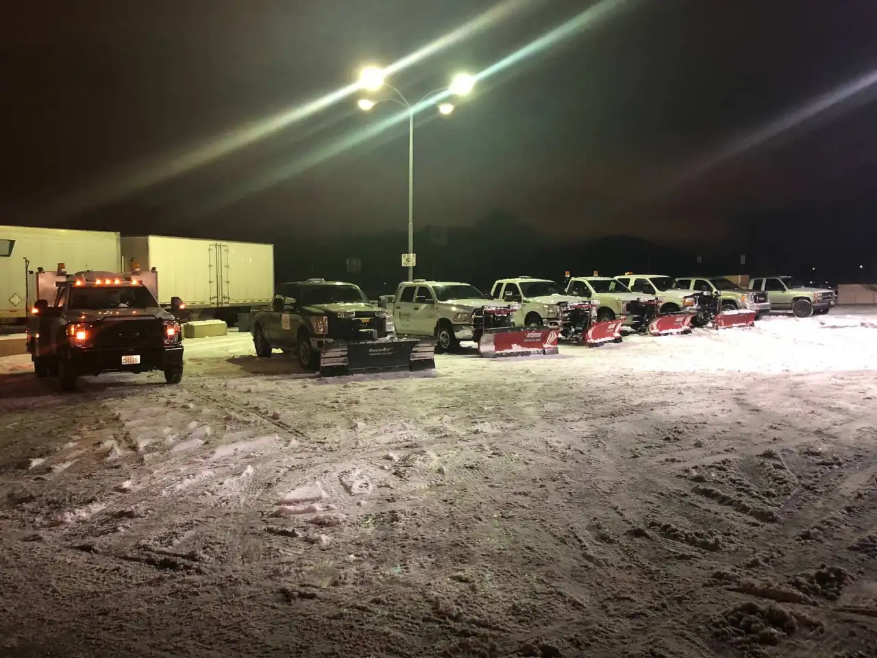 Crystal Clear plow trucks parked under the lights at night