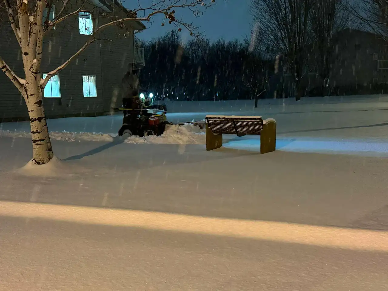 Crystal Clear sidewalk machine with a plow clearing a walkway at night