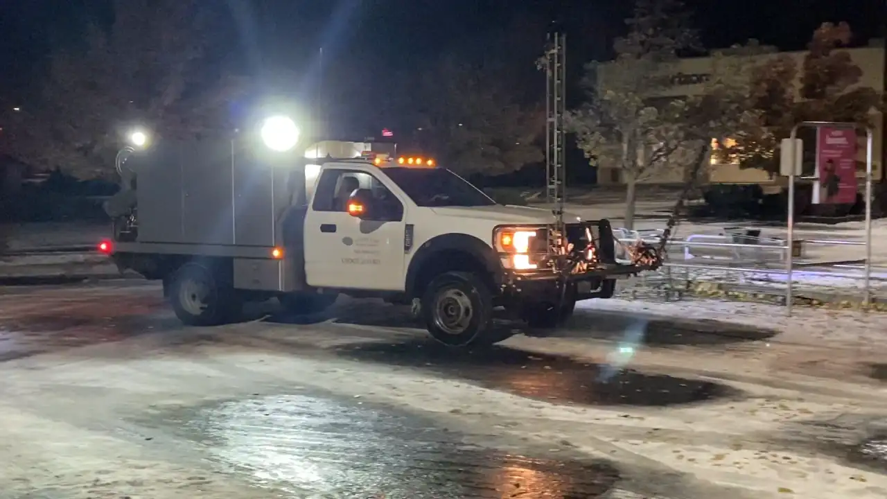 De-icing truck applying liquid treatment to an icy parking lot at night
